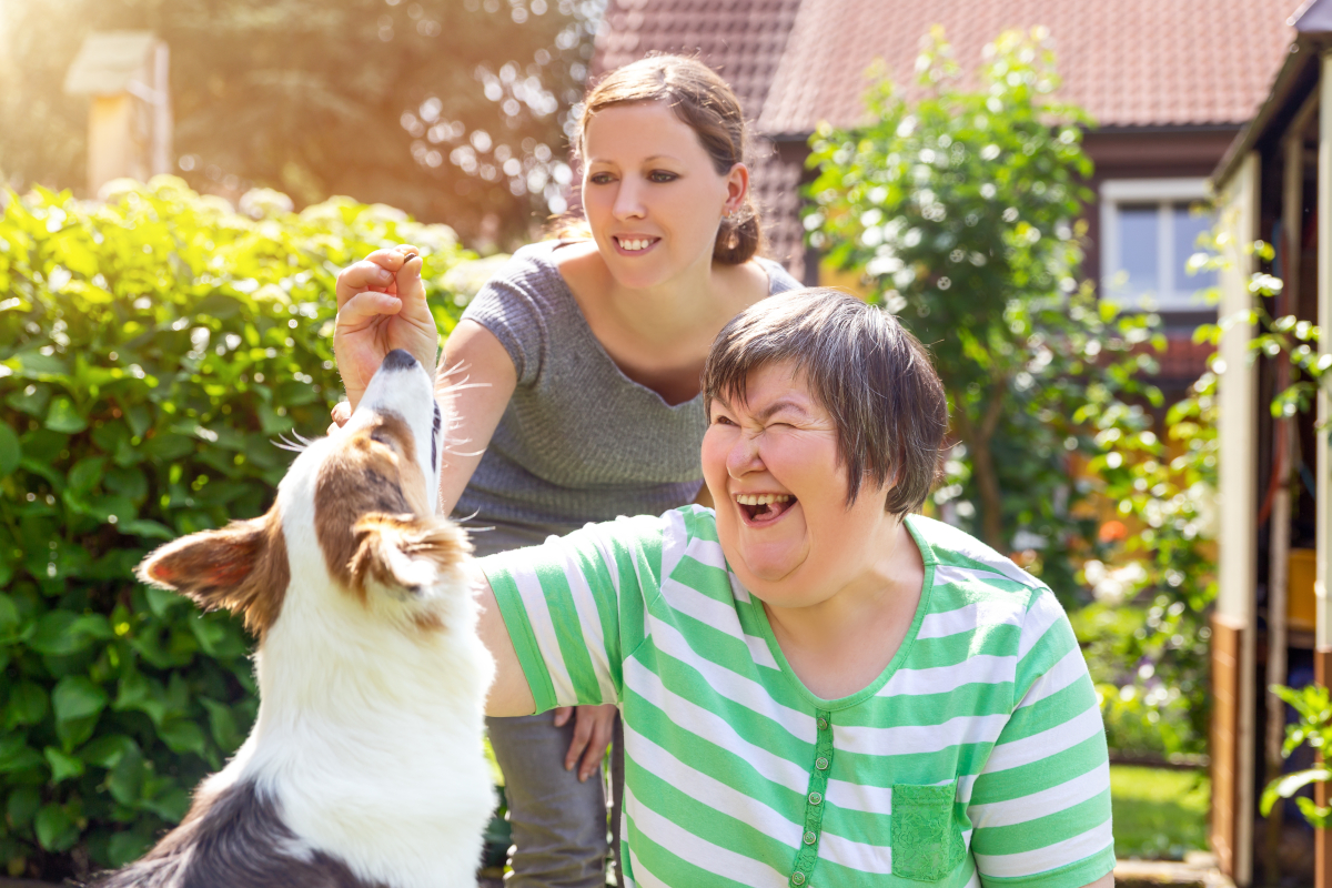 a disabled woman with a carer giving treats to a dog