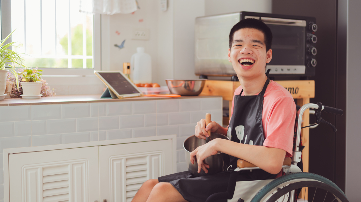 a young man in a wheel chair cooking and smiling