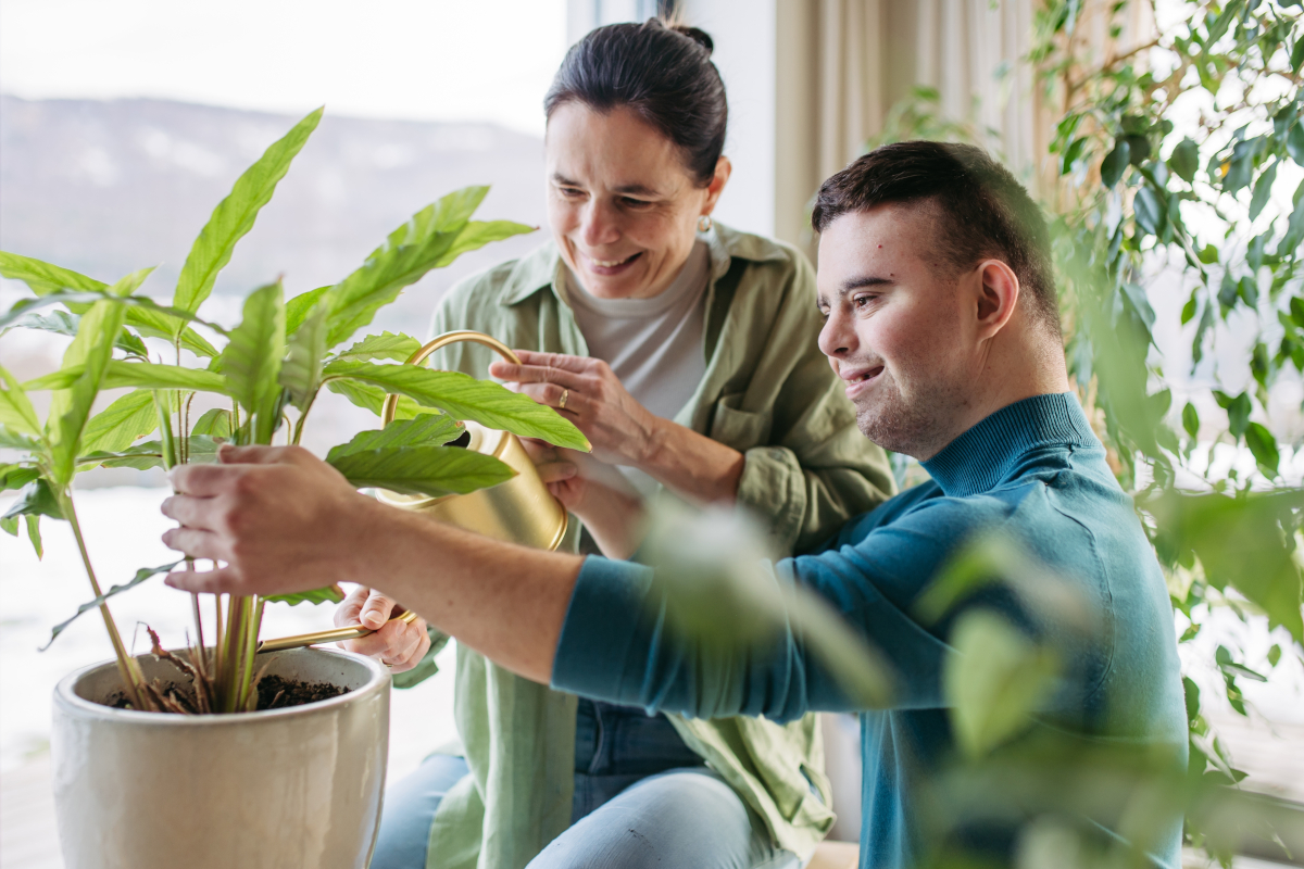 a disabled person and his carer looking after pot plant together