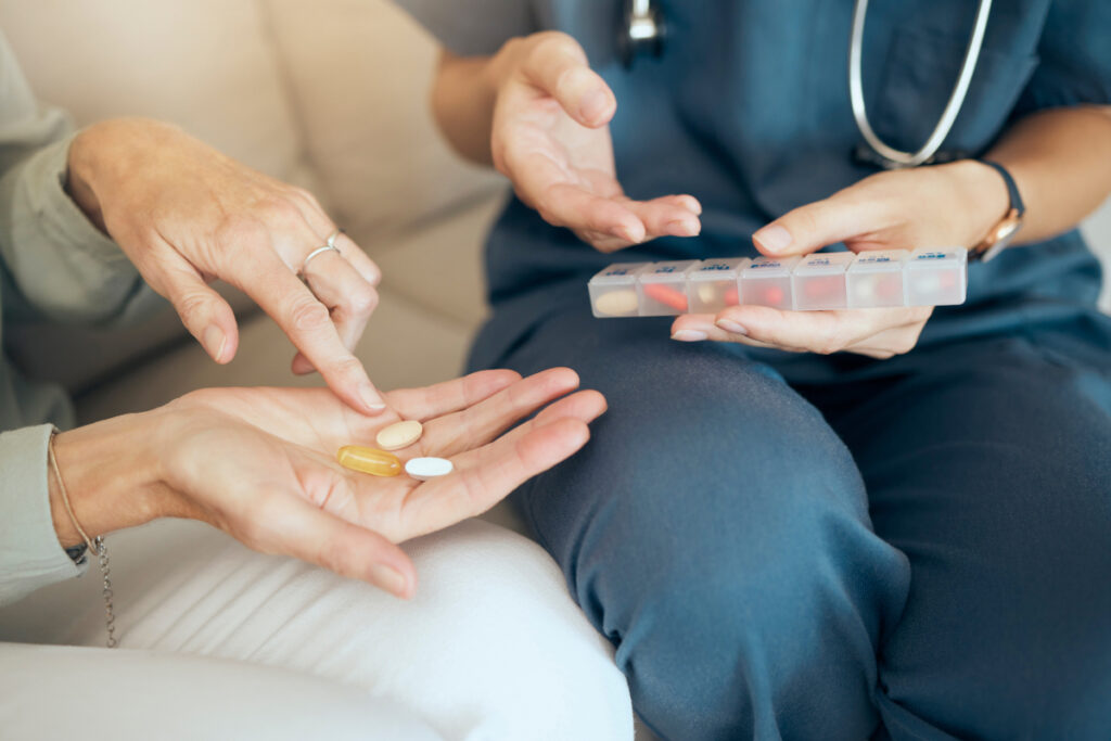 hands of a nurse and a patient holding pills 