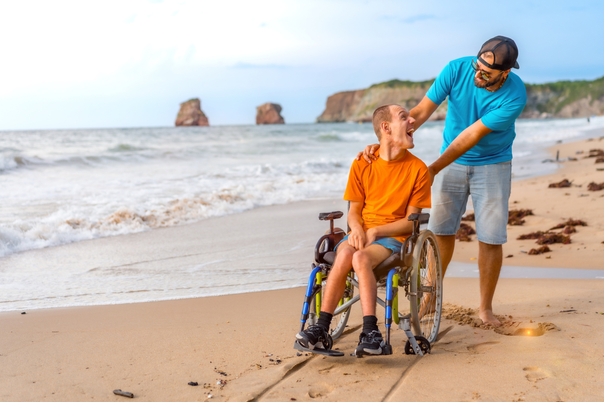 a person on a wheel chair pushed by another person on the beach